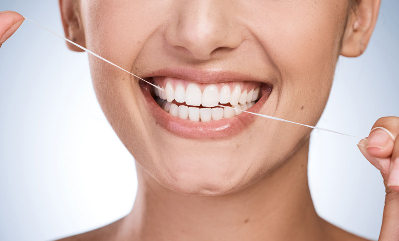 Woman, mouth and floss teeth in studio, orthodontics and cosmetics for smile on blue background.