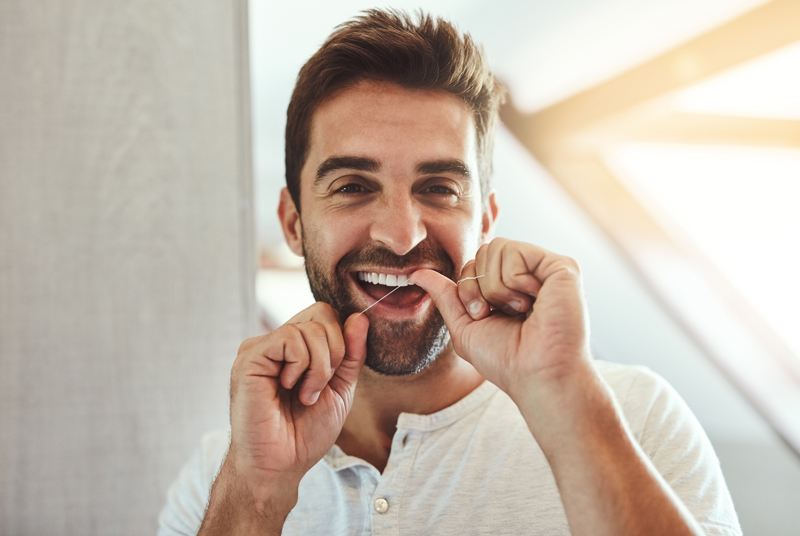 Dental floss, teeth and smile with portrait of man in bathroom for cleaning, morning and oral hygiene. Happy, cosmetics and health with face of person.