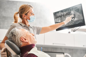 Close up of a single dental implant screw being placed into a patient's lower jaw. Focus on the screw, with the surgeon's hands blurred. No text on image.